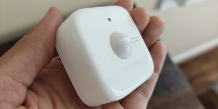Hand holding a SwitchBot presence sensor.