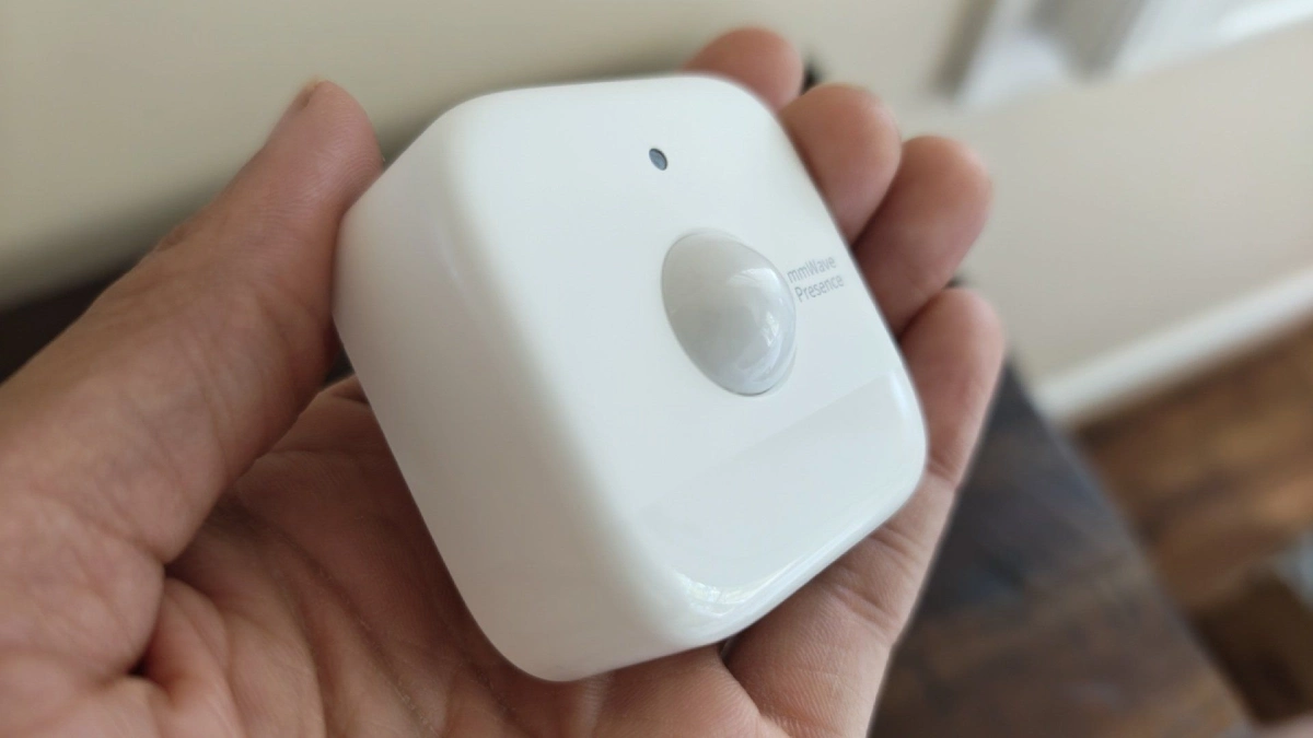 Hand holding a SwitchBot presence sensor.