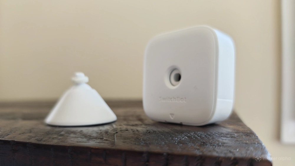 Detached SwitchBot presence sensor and stand on a wooden side table. Detached SwitchBot presence sensor and stand on a wooden side table.