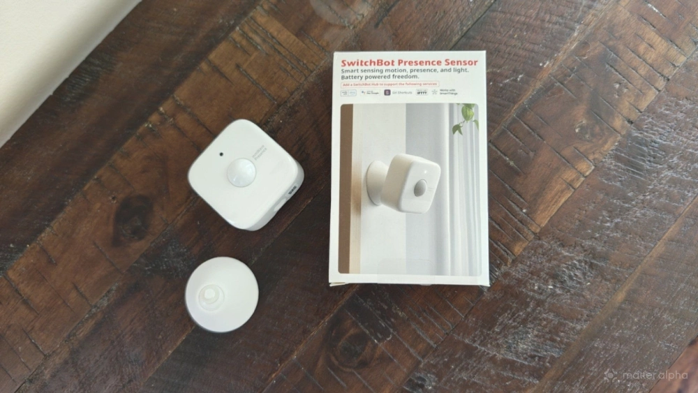SwitchBot Presence Sensor and box on a wooden table. SwitchBot Presence Sensor and box on a wooden table.