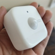 Hand holding a SwitchBot presence sensor.